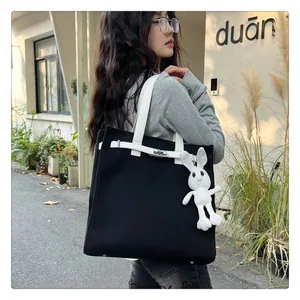 Detail of canvas tote bag with metal twist lock and cute white plush bunny charm