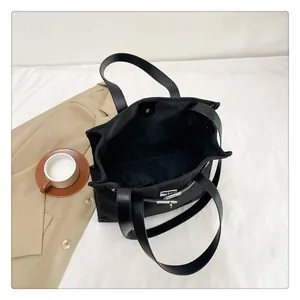 Detail view of the black canvas tote bag showing the silver twist lock and spacious interior