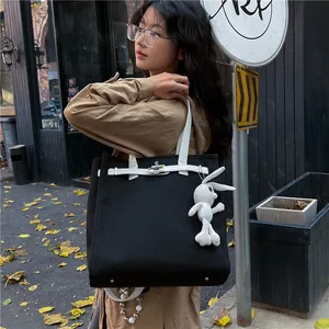 Large black canvas tote bag with white leather straps and cute bunny charm accessory