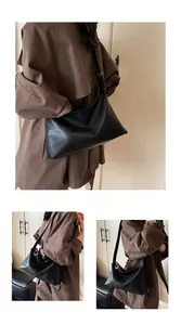 Détail d'un grand sac bandoulière noir vintage avec bandoulière large et texture cuir souple