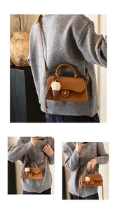 Detail van de bruine kunstlederen crossbodytas met gouden sluiting en pluche hanger