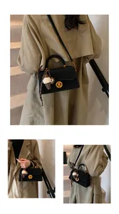 Detail van zwarte lederen crossbodytas met gouden slot en decoratieve pluche hanger
