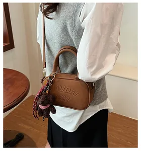 Brown bowling bag detail showing textured synthetic leather and a cute plush bear charm
