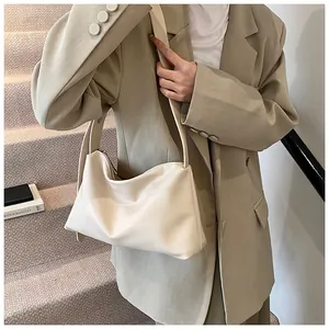 Gros plan d'un sac Boston beige souple avec large bandoulière porté par un mannequin