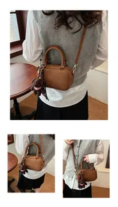 Detailed view of brown PU leather boston bag with embossed logo and bear charm detail