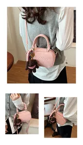 Detailed view of pink matte bowling bag with plush poodle charm and gold hardware accents