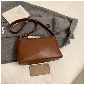 Détail d'un sac Boston vintage en cuir marron sur fond neutre avec des accessoires