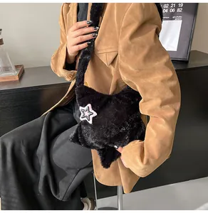 Dettaglio della borsa in peluche nera a forma di stella con ricamo rosa a contrasto