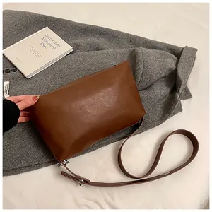 Détail du sac vintage en cuir marron sur manteau gris avec boucle en argent ajustable