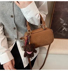Detailed shot of a brown mini bowling bag with a cute plush puppy charm accessory