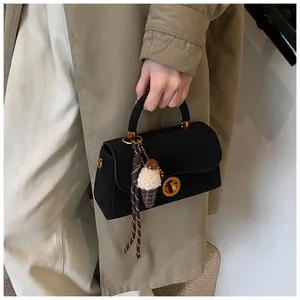 Detail van zwarte crossbodytas met matte afwerking en ijsje hanger gedragen door model