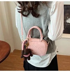 Detail of pink faux suede bowling bag featuring embossed text and cute brown bear charm
