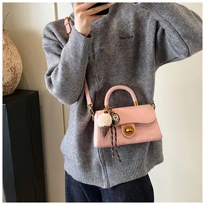 Detail van roze suède crossbodytas met gouden draaisluiting en pluche ijsje hanger
