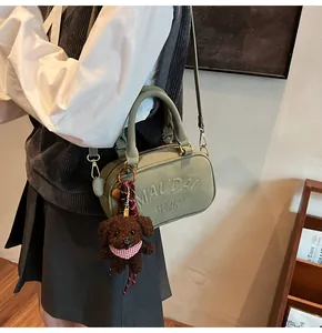 Detail of green leather bowling bag featuring MAUDAI BEAR embossing and a teddy bear charm