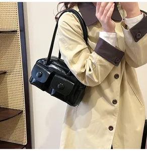Detail of glossy black PU leather shoulder bag with double pockets and retro buckle