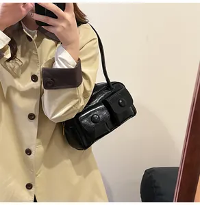 Close-up of black glossy leather shoulder bag featuring two front flap pockets and buttons