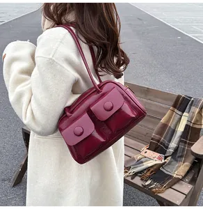Close-up of wine red glossy leather shoulder bag with double front flap pockets