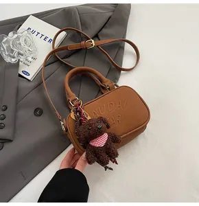 Detail of brown bowling bag with embossed bear logo and cute teddy bear pendant
