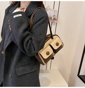 Detail of vintage two-tone shoulder bag with large buckle pockets worn by a model