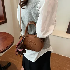 Brown bowling bag with bear charm and embossed logo shown in a stylish lifestyle setting