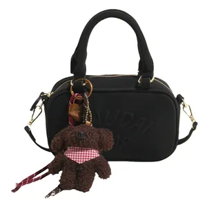 Minimalist black bowling handbag with textured knit fabric and brown teddy bear charm
