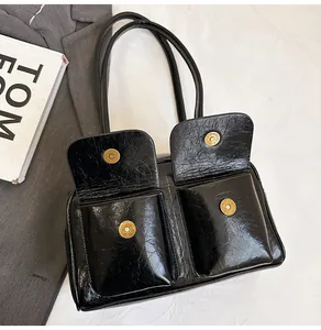 Detail of black glossy faux leather shoulder bag with vintage dual pockets and metal buckles