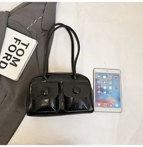 Close-up of black glossy PU leather handbag with two front pockets and large buttons