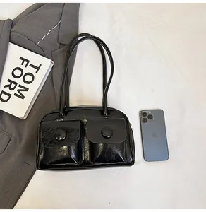 Detail of glossy black multi-pocket shoulder bag with metallic buckle flip covers