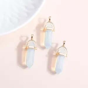 Three hexagonal opal crystal pendants with gold metal caps on a pink background