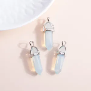 Three hexagonal opal crystal pendants with silver metal loops on a beige background
