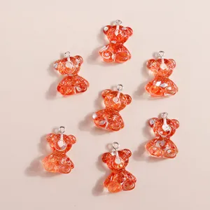Gros plan de pendentifs ours en résine orange avec paillettes dorées et anneaux en argent