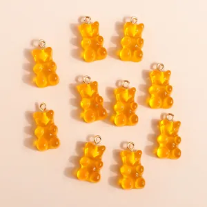 Macro shot of 10 translucent amber resin gummy bear charms with golden loops for DIY jewelry