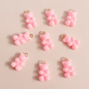 Macro shot of 9 pink resin gummy bear charms with golden rings for DIY jewelry projects