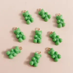 Flat lay of green resin bear charms with golden loops for DIY jewelry making