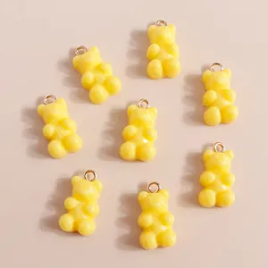 Detailed view of yellow gummy bear resin pendants with gold loops for DIY jewelry
