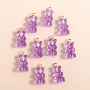 Close-up of translucent purple resin gummy bear charms with rose gold rings for DIY jewelry