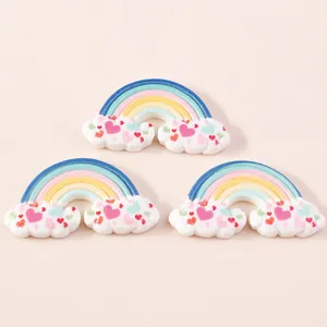 Detail of three resin rainbow cloud charms with small hearts for DIY phone case decor