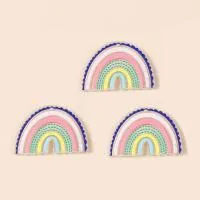 Close-up of rainbow-shaped acrylic DIY charms with tiny dots and pre-drilled holes