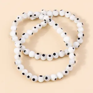 Detailed close-up of three white resin evil eye bead bracelets with black dot motifs
