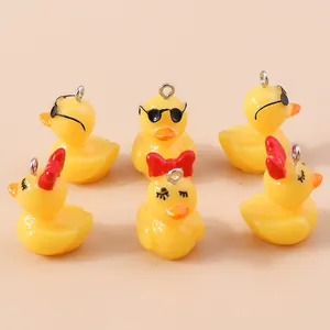 Dettaglio di simpatiche papere gialle in resina con occhiali e fiocco per gioielli DIY