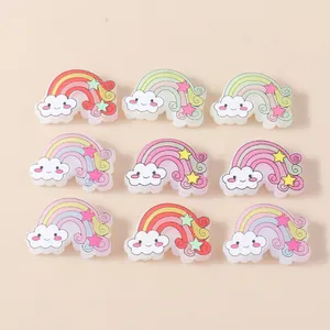 Flat lay of nine rainbow resin accessories with smiling clouds for DIY crafts decoration