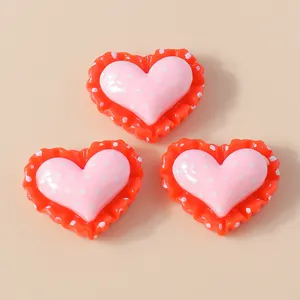 Detailed view of resin heart charms with pink polka dots and orange lace for DIY crafts