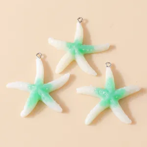 Detailed view of three resin starfish charms in white and green gradient with metal rings