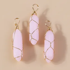 Detail van drie roze zeshoekige kristallen hangers met gouden draadwikkeling