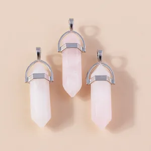 Drie zeshoekige rozenkwarts kristallen hangers met zilveren oogje op beige ondergrond
