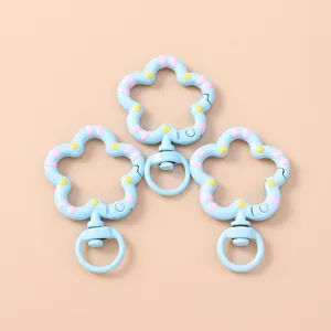 Primer plano de mosquetones metálicos con forma de flor azul claro y rayas pintadas