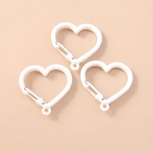 Dettaglio di tre chiusure a molla bianche a forma di cuore per gioielli fai-da-te