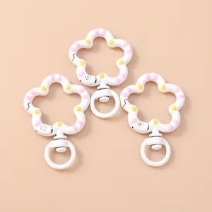 Detalle de tres mosquetones giratorios en forma de flor blanca con lunares rosas y amarillos