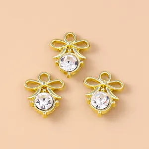 Three gold bow pendants with pearl and rhinestone accents on a beige background