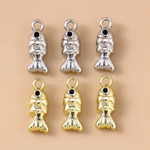 Close-up van gouden en zilveren koi-visbedeltjes voor DIY-sieraden op beige achtergrond